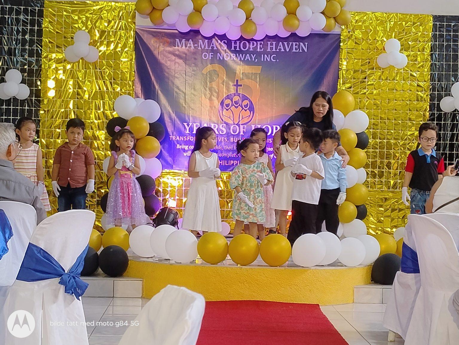 Children and a caregiver on stage at the haven's anniversary celebration