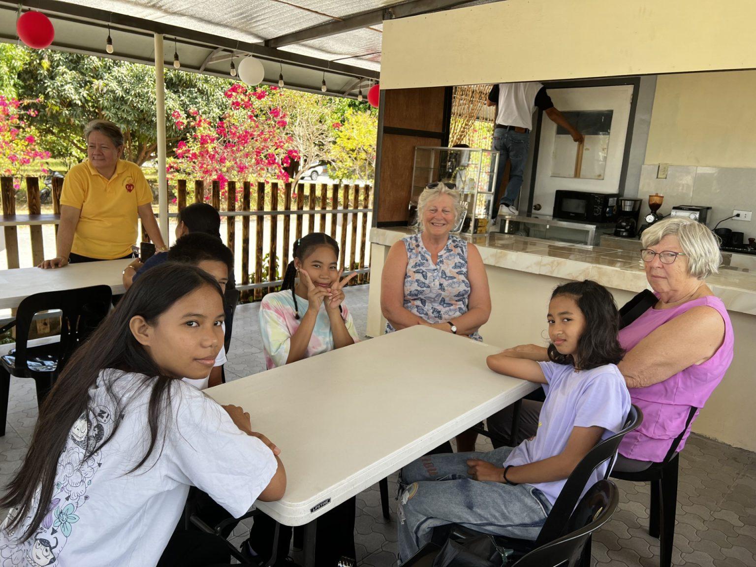 Caregivers and children seated together around a table at the haven