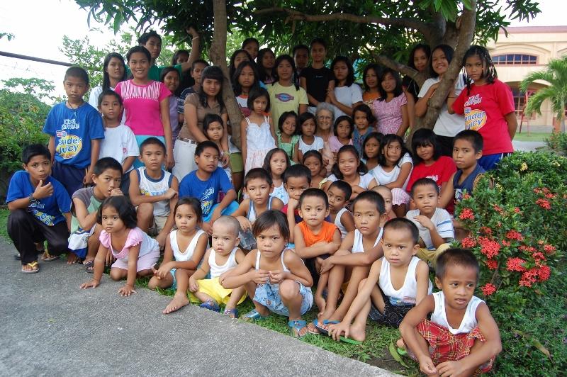 Children and volunteers gathered outdoors among flowering plants